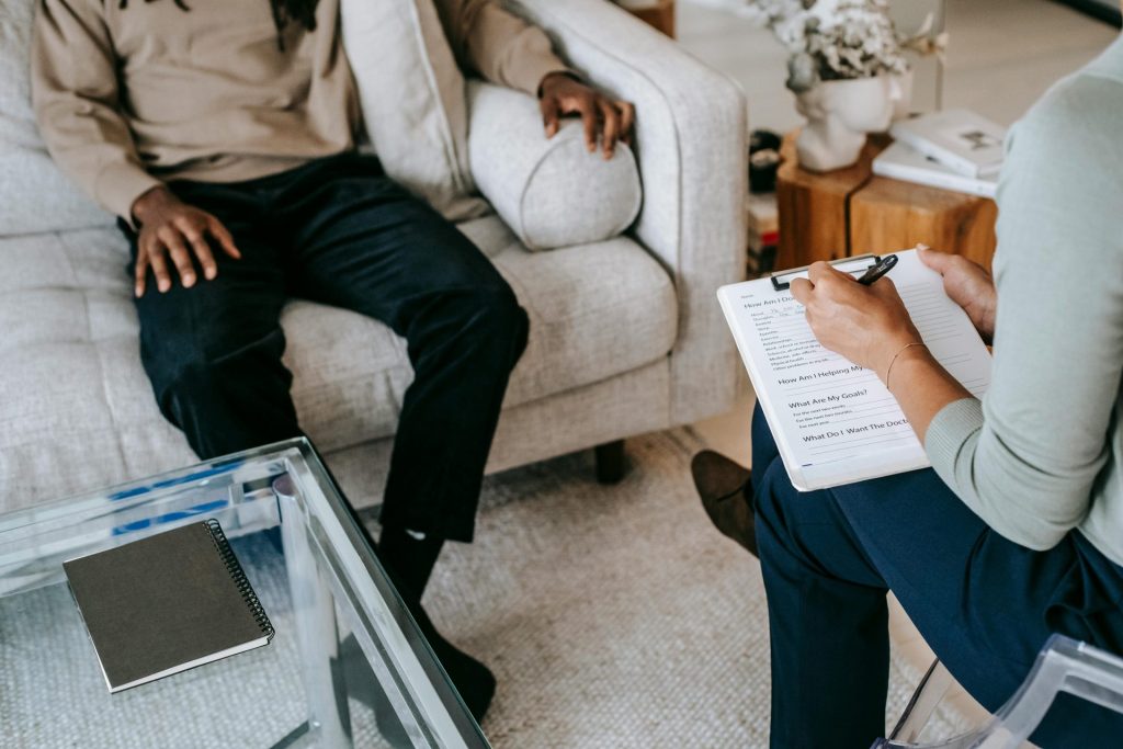 Psicólogo tomando notas con cliente sentado en un sofá